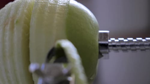 Slow motion of person struggling to finish peeling, cutting and core green juicy apple skin with met