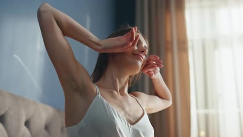 Woman Stretching in Bed with Morning Sunlight