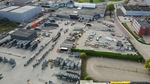 Stunning aerial of a truck driving onto a large storage yard of an industrial company on a sunny day