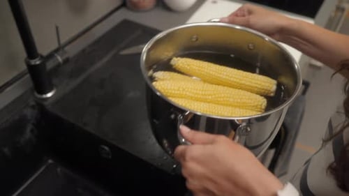 Woman Prepares Corn on the Cob in Kitchen
