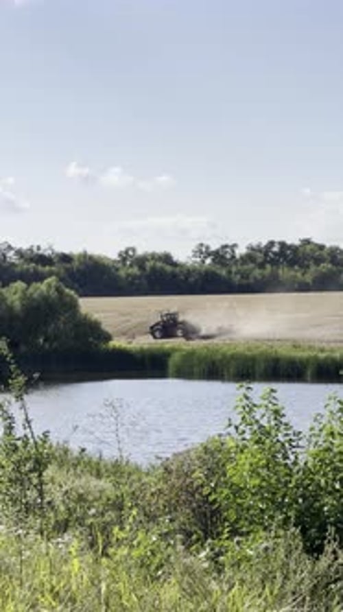 Ein Traktor pflügt ein Feld entlang eines Flusses