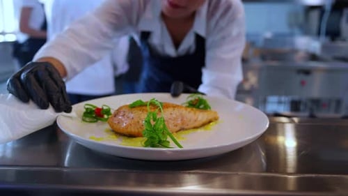 Chef Plates Salmon with Artistic Garnishes in Kitchen