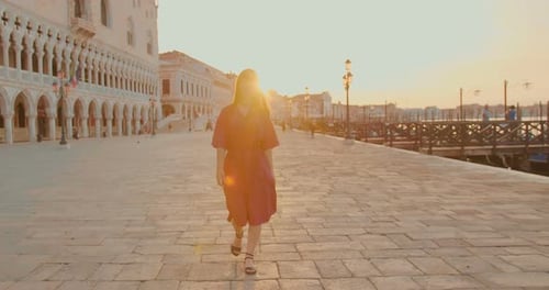 Woman Walks in European City at Sunset