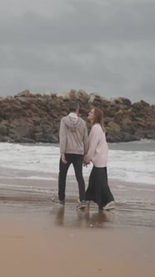 Young Couple Walking on Beach on Cloudy Day