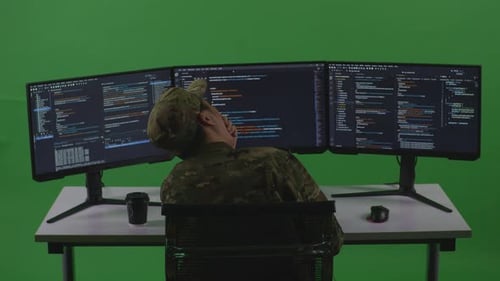 Back View Of Man Soldier Developer Yawning While Write Code With Multiple Screens In Green Screen