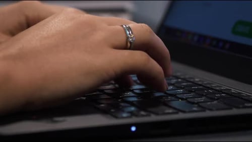 Woman Typing on Laptop Keyboard in Office