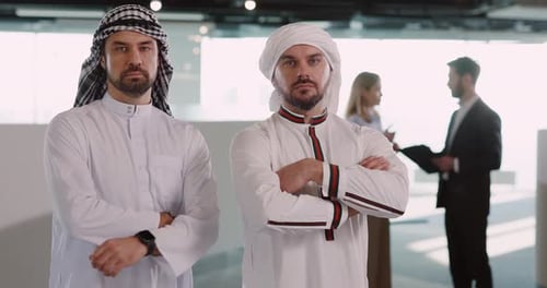 Two men standing with arms crossed in a workplace