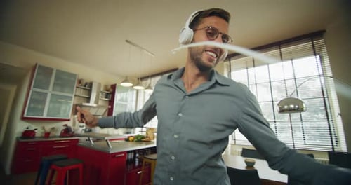 Authentic close up shot of an young carefree happy man wearing white headphones is having fun to l