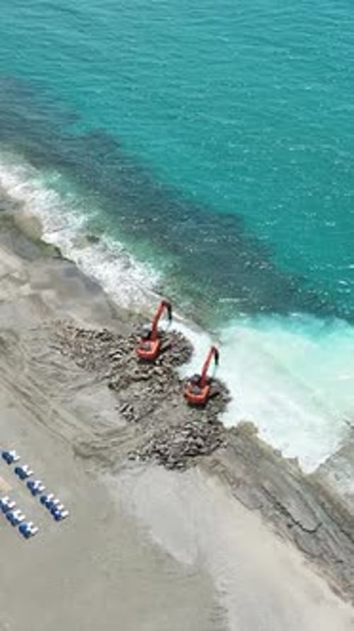 Vertical Video Shaping Nature's Canvas Machine Sculpting a Stone Beach with Turquoise Strokes