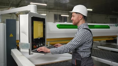 Worker Controls CNC Machine for Wood Panel Cutting