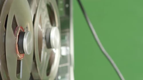Tape recorder playing magnetic deck, closeup side view, green screen background