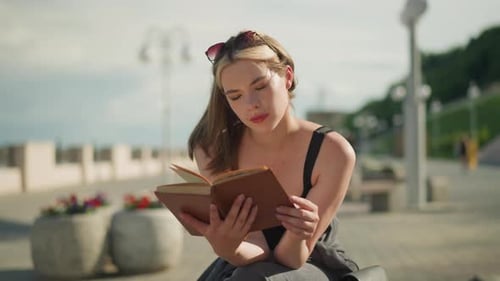 Young Woman Reading Book Outside on Bench