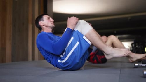 Des hommes athlétiques au gymnase faisant une série de situps actifs en forme de combattants masculins en tenue de sport