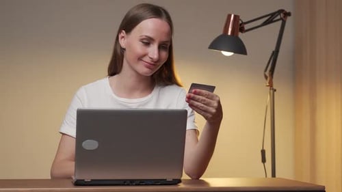 Happy Young Attractive Woman Shopping Online Using a Laptop Computer Using a Credit Card at Home