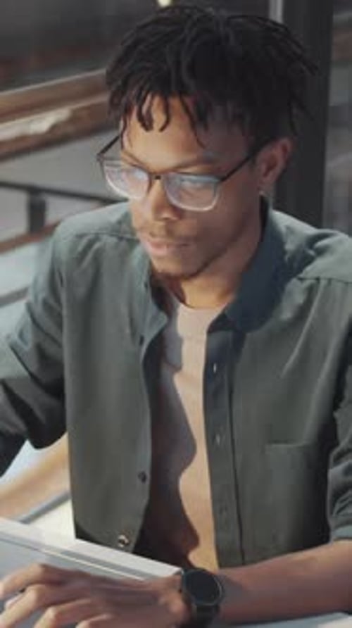Vertical Portrait of Positive African American Office Worker Sitting at Desk