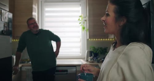 Woman Stirring Drink While Talking to Man in Kitchen