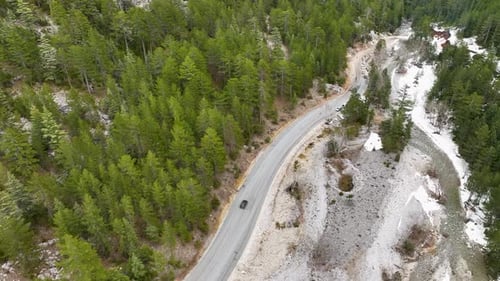 Bird'seye View Cars Drive Along a Picturesque Zigzag Serpentine Road Through a Dense Spruce Forest
