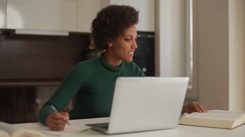 Portrait of Curly African College Student Female Writing Notes Lesson Summary Using Laptop Typing