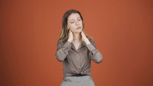 Young Woman Massaging Sore Neck on Orange Background