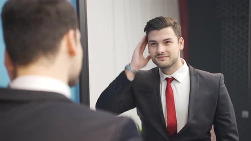 Young Man in Suit Adjusting Himself in Mirror