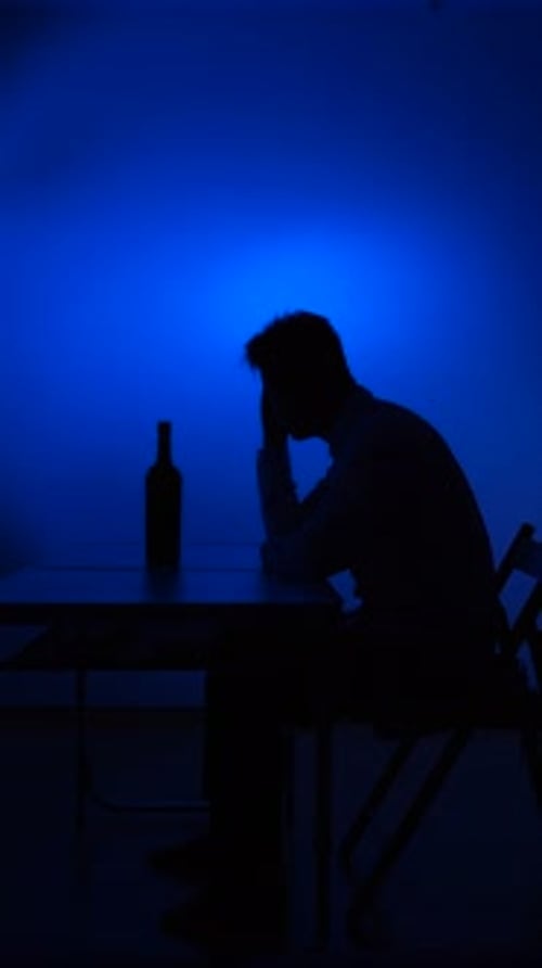 Silhouette of Man at Desk Under Blue Lighting