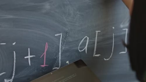 Student Writing on Chalkboard While Using Tablet