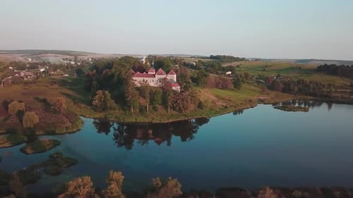 Elevating pan drone shot of a castle next to a lake that reflects it. Shot in 4K