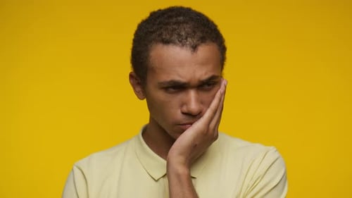 Contemplative Young Adult Thinking on Yellow Background