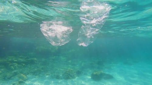 Plastic pollution in sea ocean - big environmental problem. Plastic bag and bottle floating in sea.