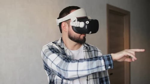 Male gamer using a VR headset to access the metaverse while gaming online at home.