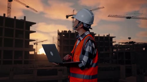 Side View Of Asian Male Engineer Working On A Laptop At Building Site