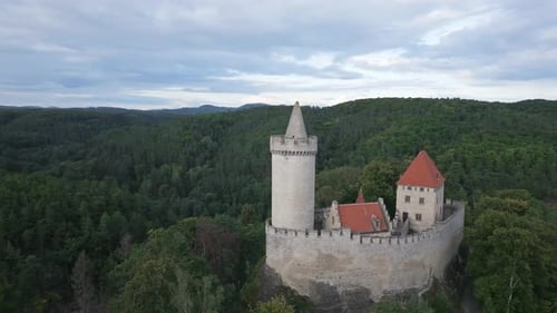 Flight of a drone camera around the tower of a medieval castle in the middle of endless forests.