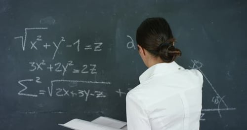 Teacher Writes Math Equations on Chalkboard