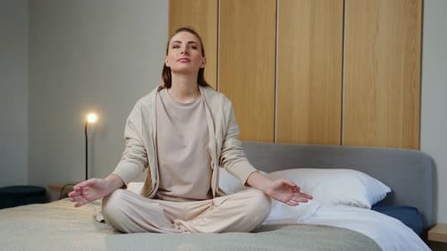 Woman Meditating Calmly on Bed in Relaxing Bedroom