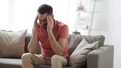 Man Seated on Couch Massaging Temples