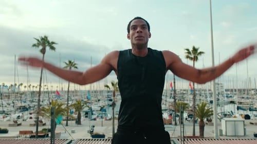 Fit Black Man Doing Jumping Jacks by the Marina