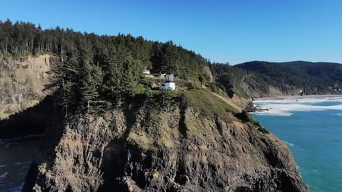 Drohne fliegt um einen Leuchtturm auf einer Klippe in der Ferne. Am späten Nachmittag, und das Meer und die Klippe sind
