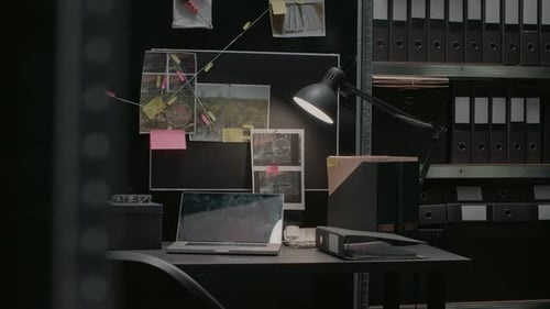 Cluttered Desk with Laptop and Photos on Wall