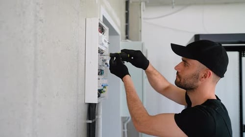 Electrician Works in a Switchboard with an Electrical Connecting Cable