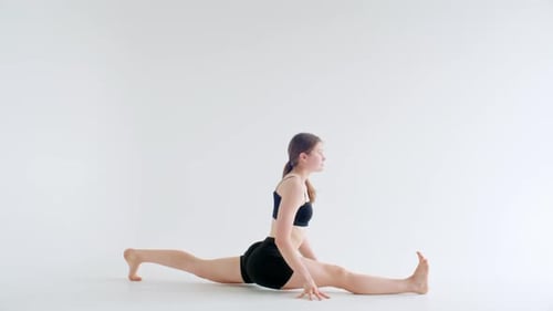Niña practicando la postura de la paloma real con una sola pierna durante una sesión de estiramiento de yoga