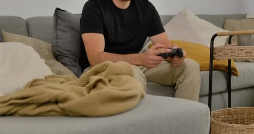 Man plays video games on couch at home