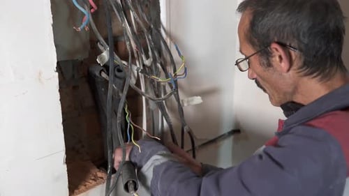 Electrician Working on Intricate Wiring in a Home