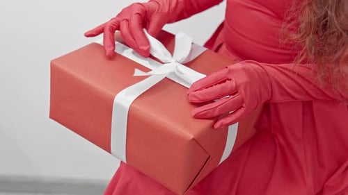 Hands Tie White Ribbon on Wrapped Birthday Gift
