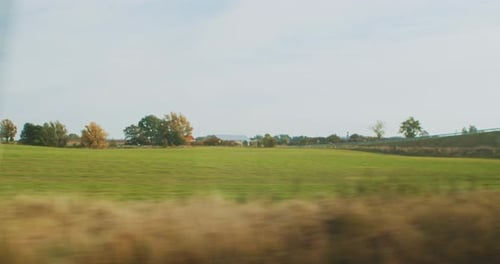 Herbstlandschaft mit Feldern, Hügeln und Weiden aus dem Fenster eines Eisenbahnwaggons