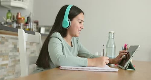 Teen Girl Studying with Tablet and Headphones at Home