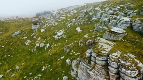 Scenic aerial drone flight with fog landscape in mountains. Misty fog blowing over rocks and hills.