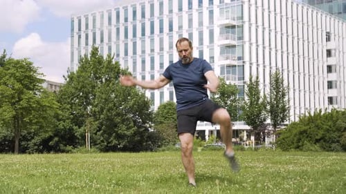 A Handsome Middleaged Caucasian Man Warms Up His Legs in a Park