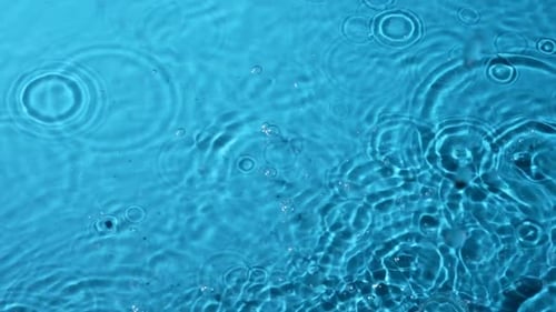 Water Droplets Create Ripples on Blue Surface