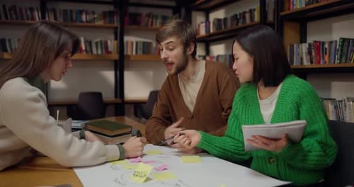 Un étudiant concentré et actif avec ses collègues féminines assis à la table et écrivant