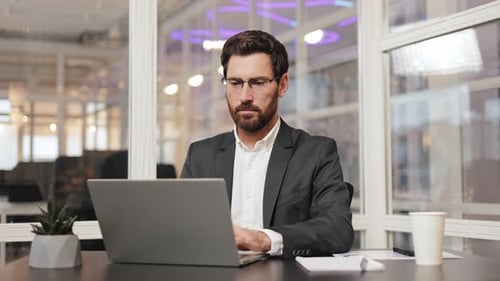 Businessman Working on Laptop in Modern Office